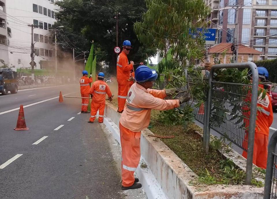 Homens em operação de limpeza na avenida 